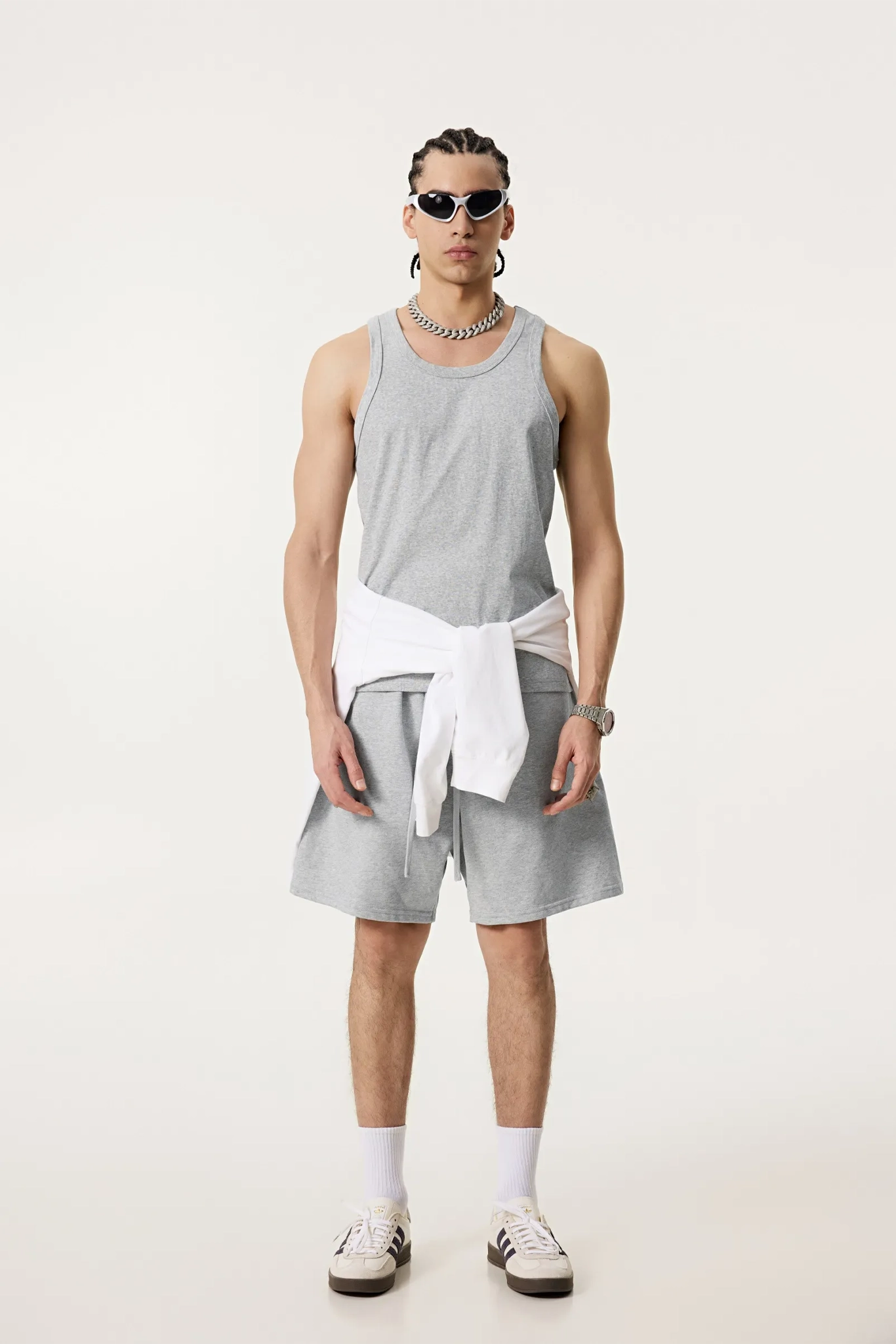 Person wearing a gray tank top and shorts with a white belt on a white background