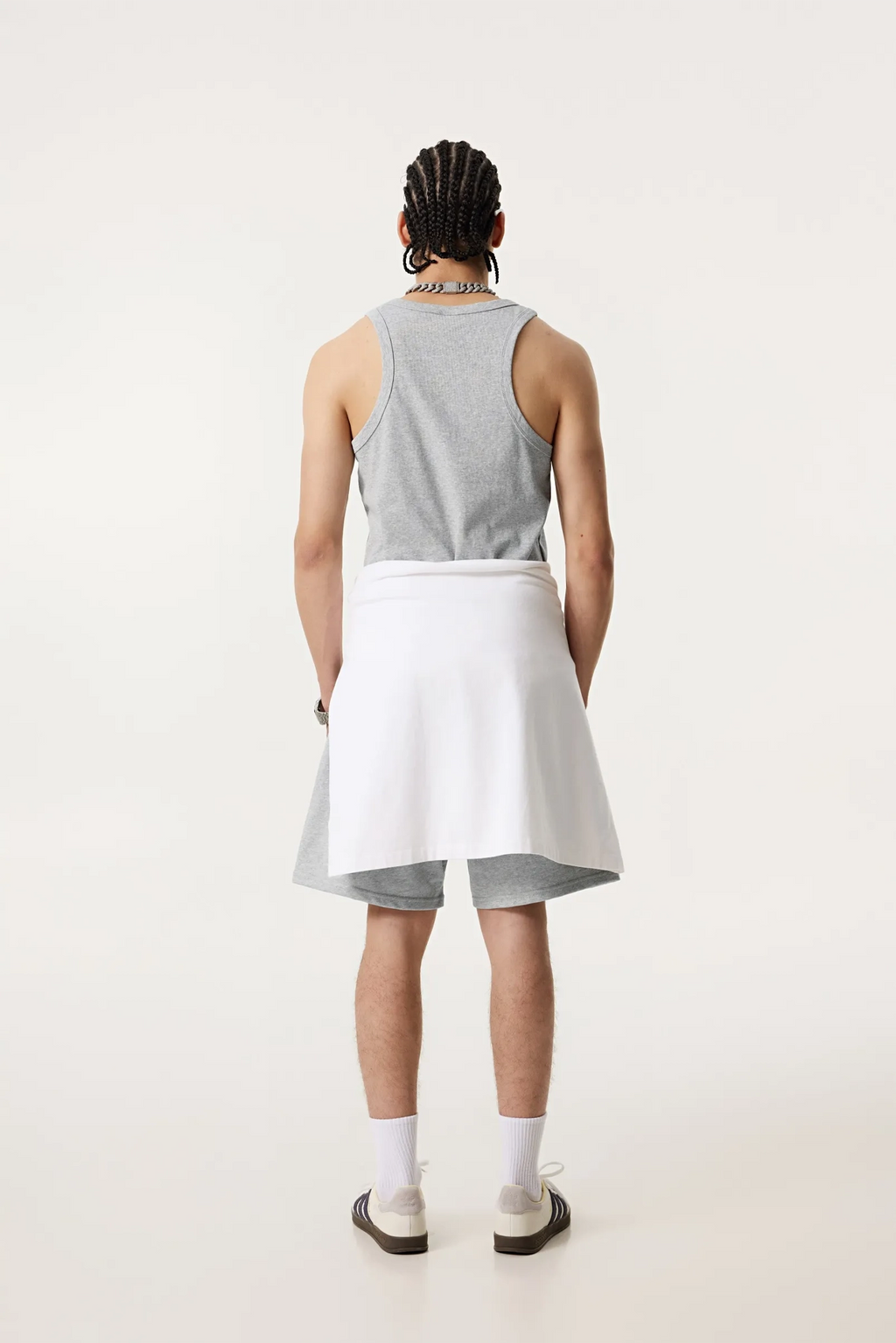 Person wearing a gray tank top and white skirt on a white background