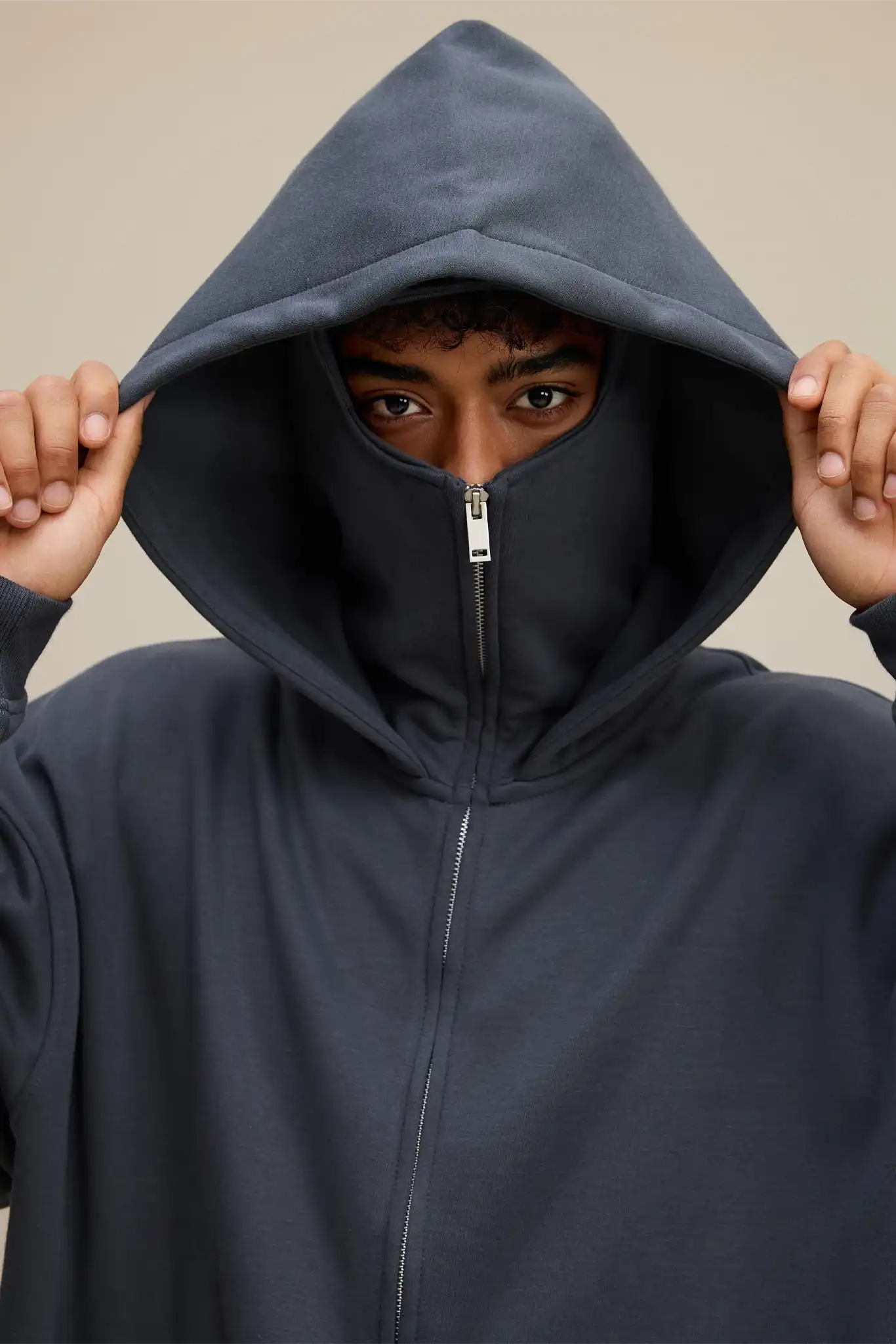 Person wearing a dark blue hoodie with a zipper, standing against a neutral background