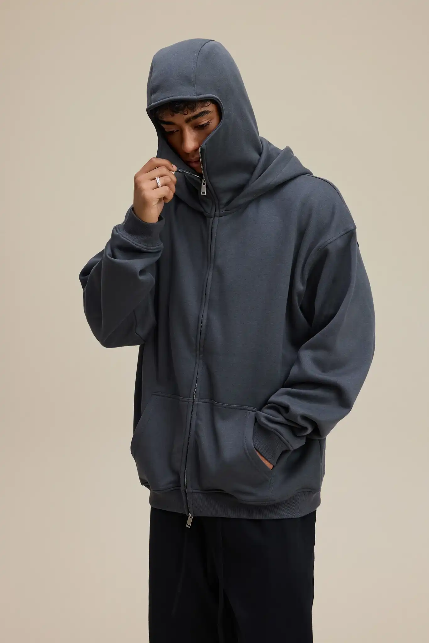 Person wearing a dark gray hoodie on a beige background