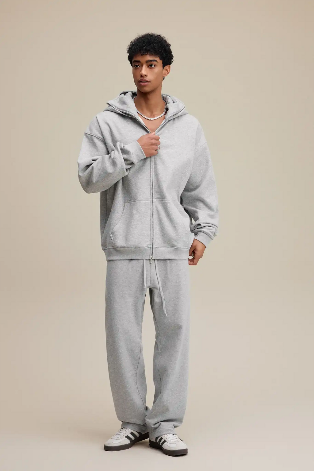 Person wearing a gray tracksuit on a beige background
