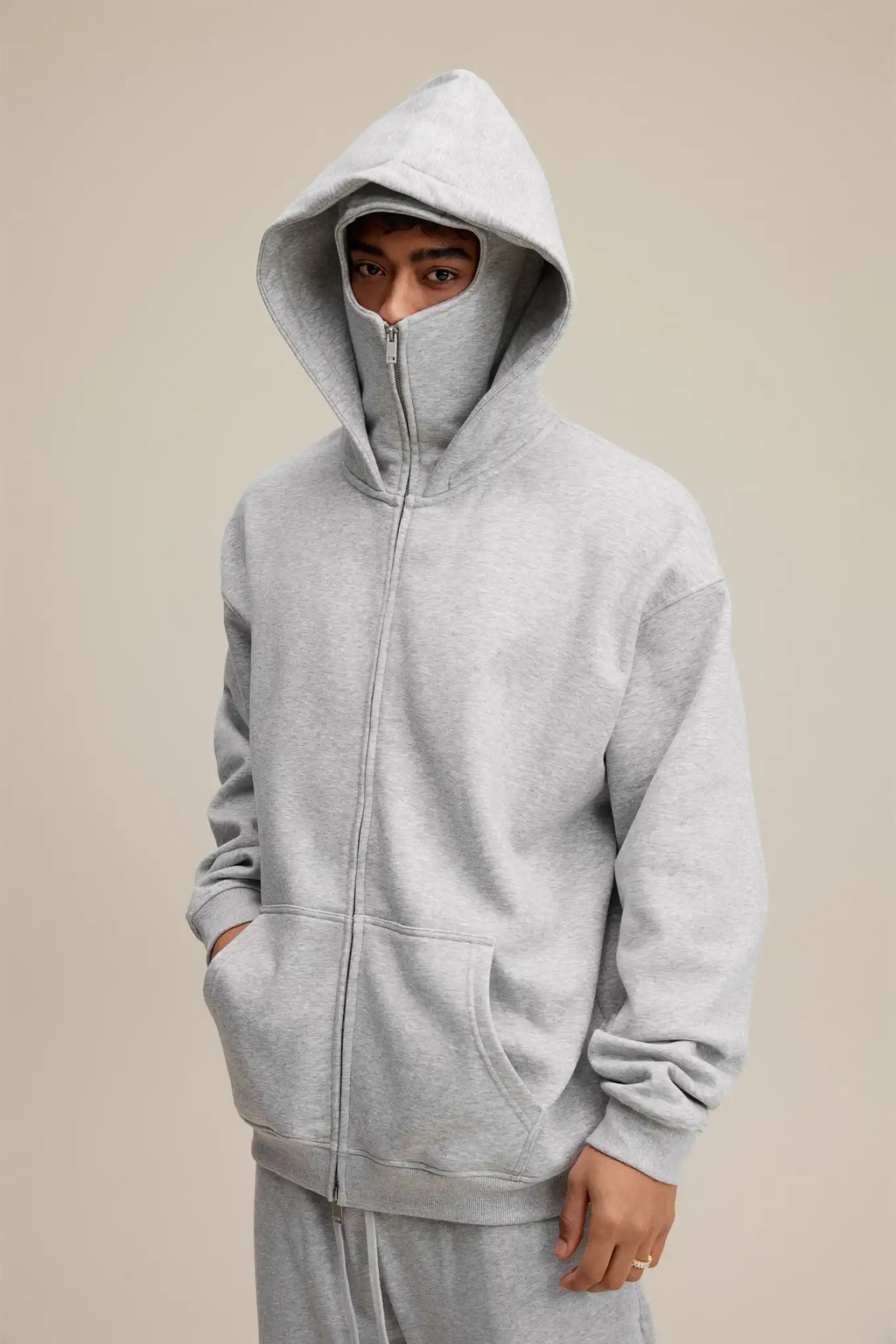 Person wearing a gray hoodie with a neutral background
