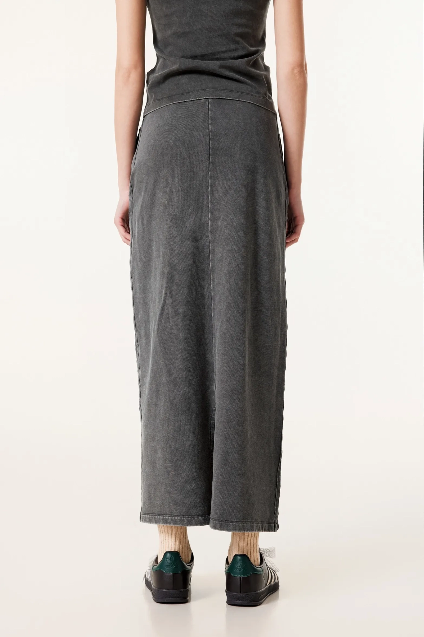 Person wearing a long dark gray skirt on a white background