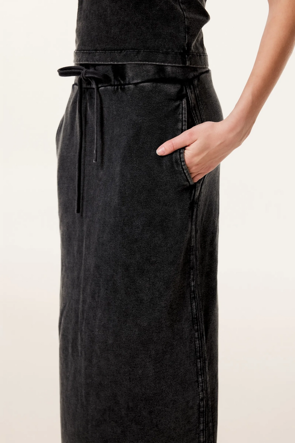 Black apron worn by a person on a beige background