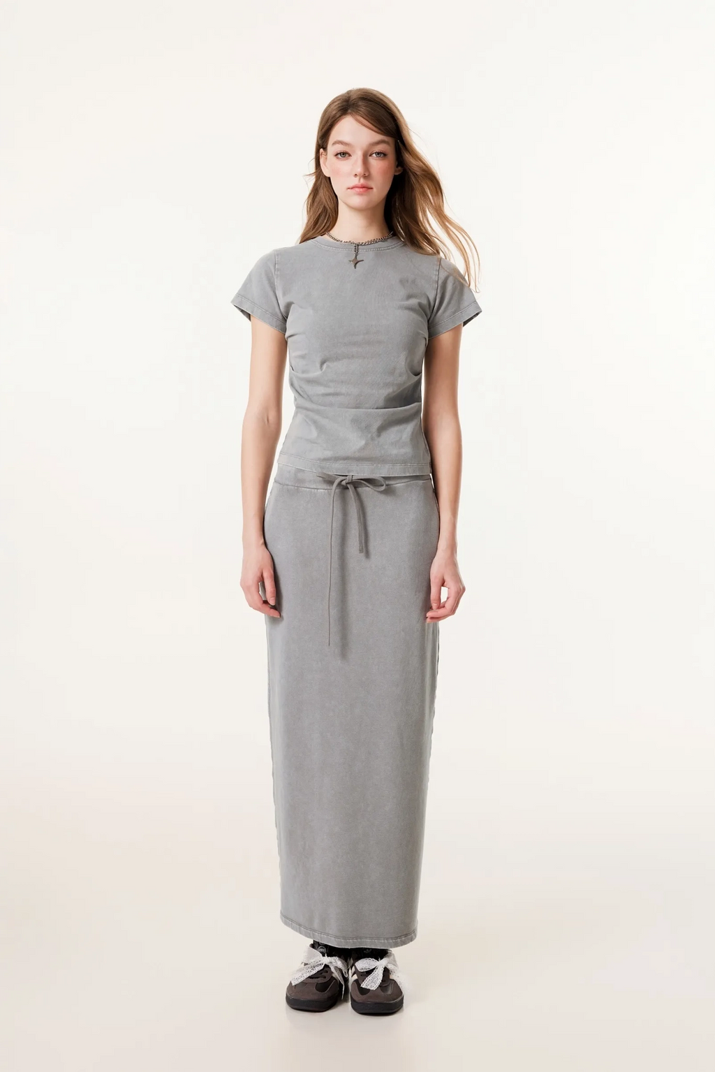 Woman wearing a gray outfit with a long skirt on a white background