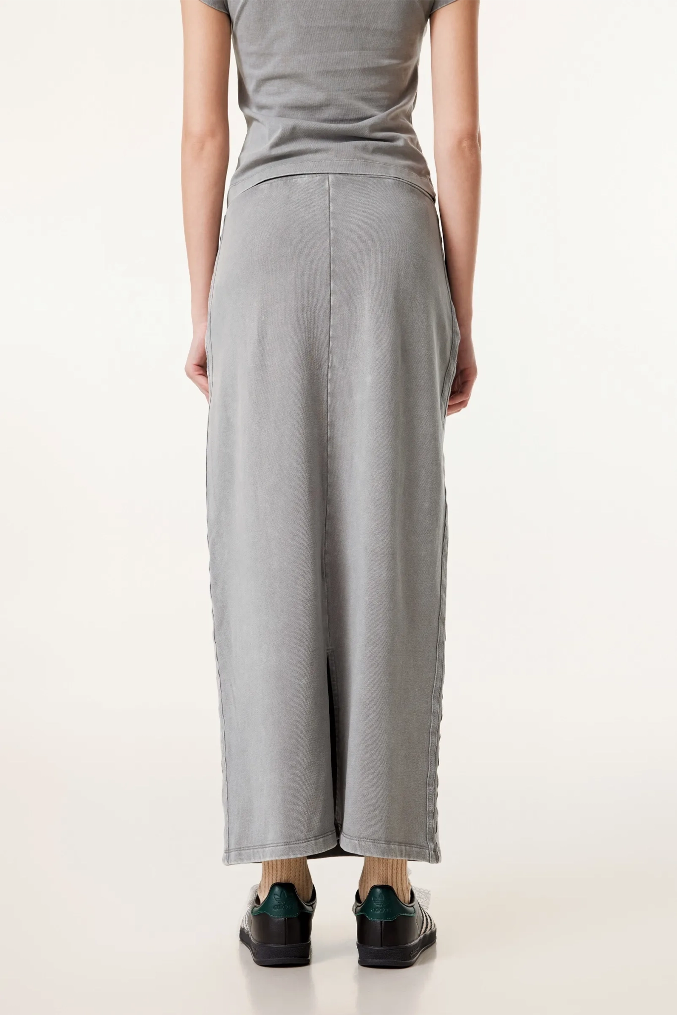 Person wearing a gray dress with a plain background