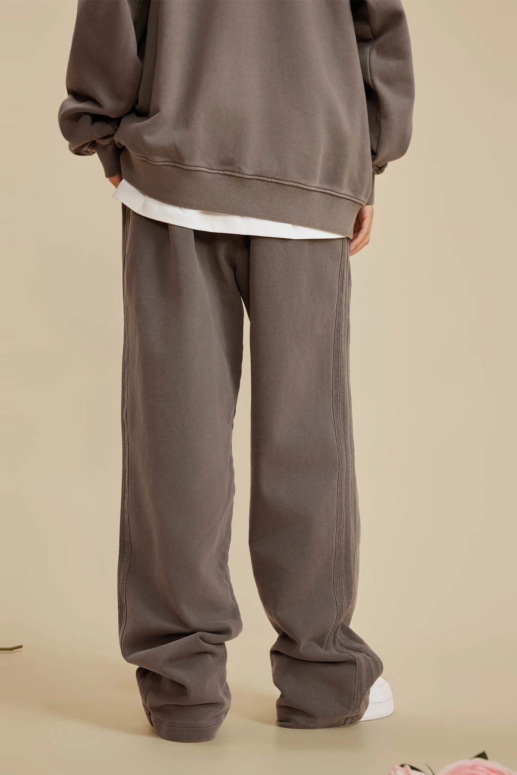 Person wearing a brown tracksuit on a beige background
