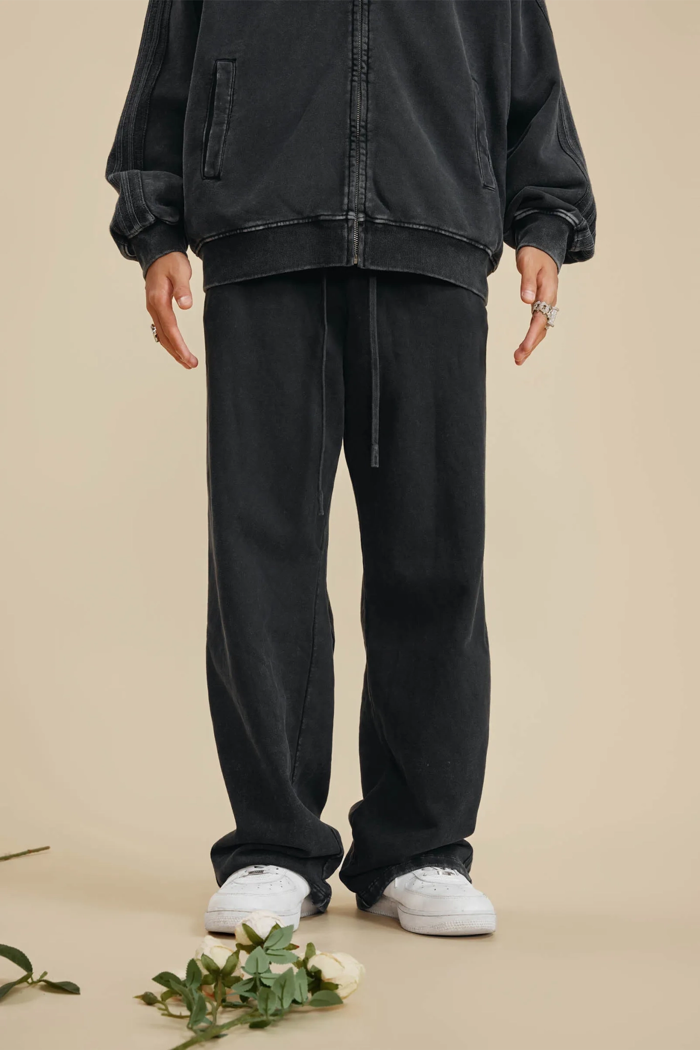 Person wearing a black jacket and pants on a beige background