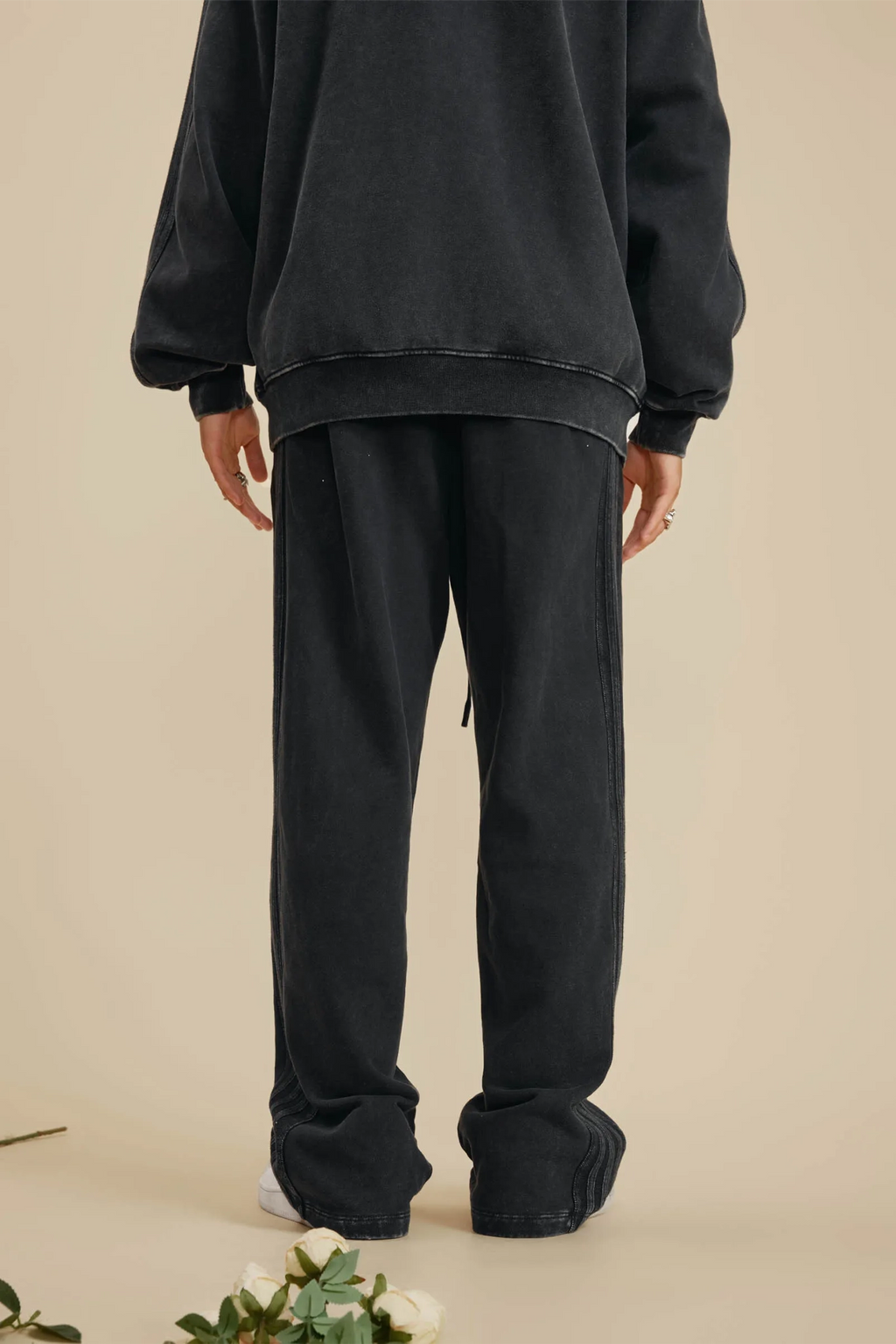 Person wearing a black outfit with a beige background