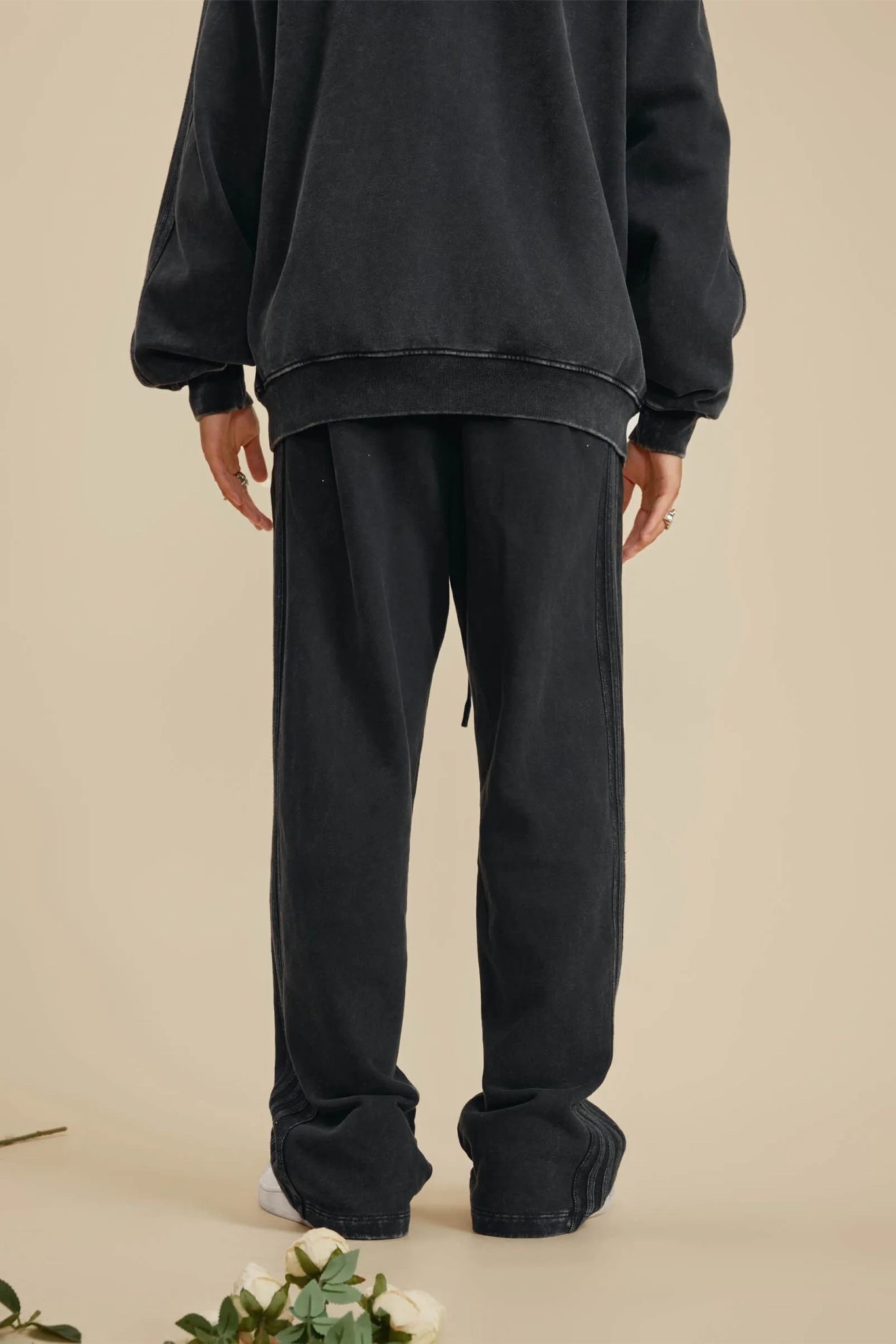 Person wearing a black outfit with a beige background