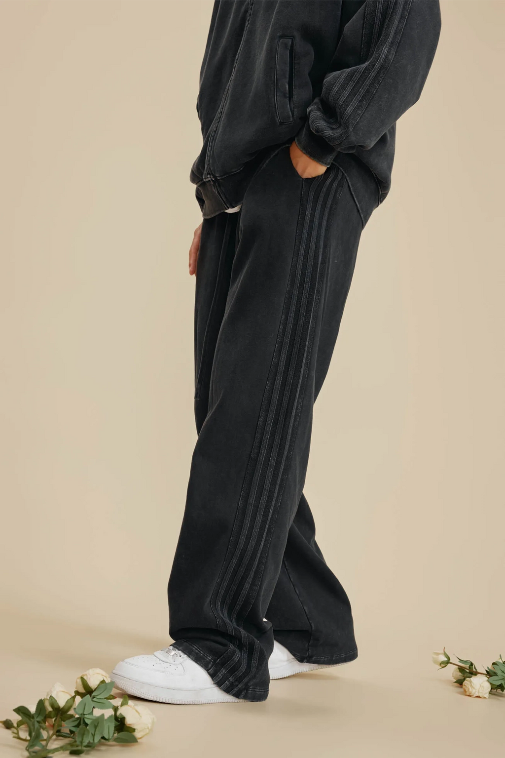 Person wearing black pants and white shoes on a beige background