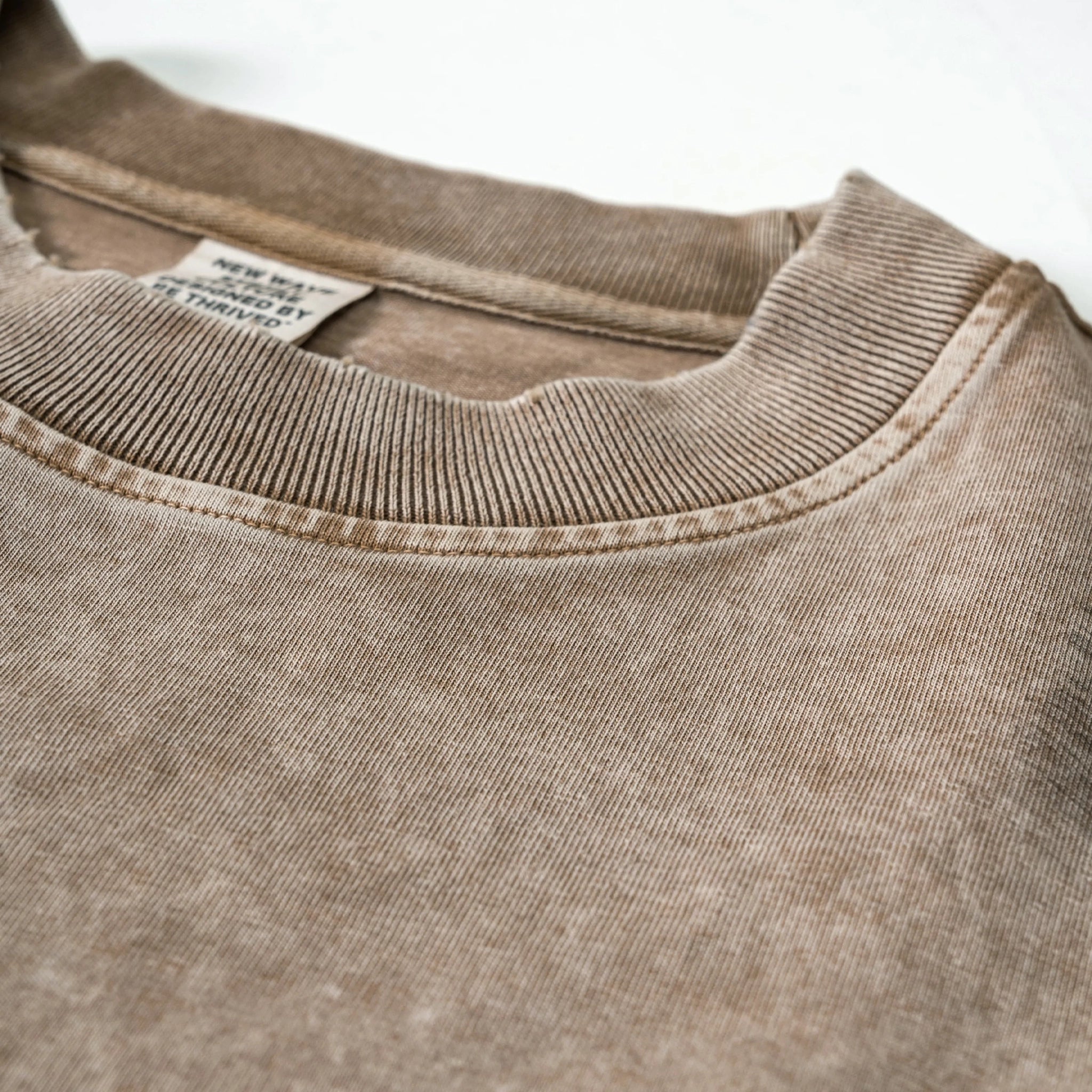 Close-up of a brown sweatshirt collar with a visible tag on a white background