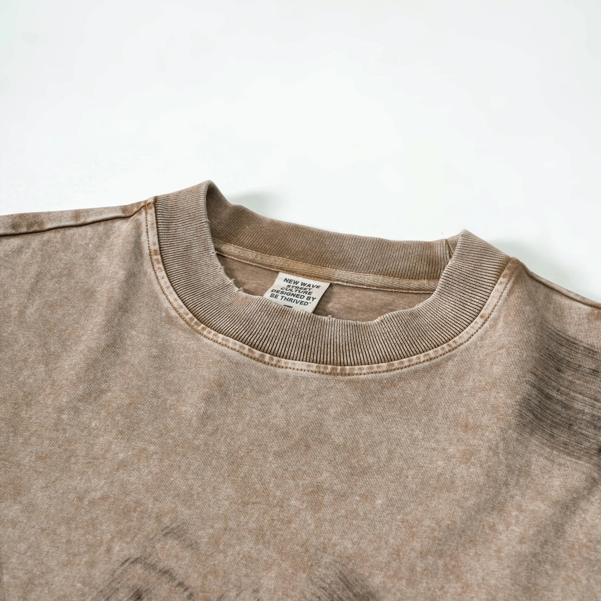 Close-up of a brown sweatshirt with a tag on a white background