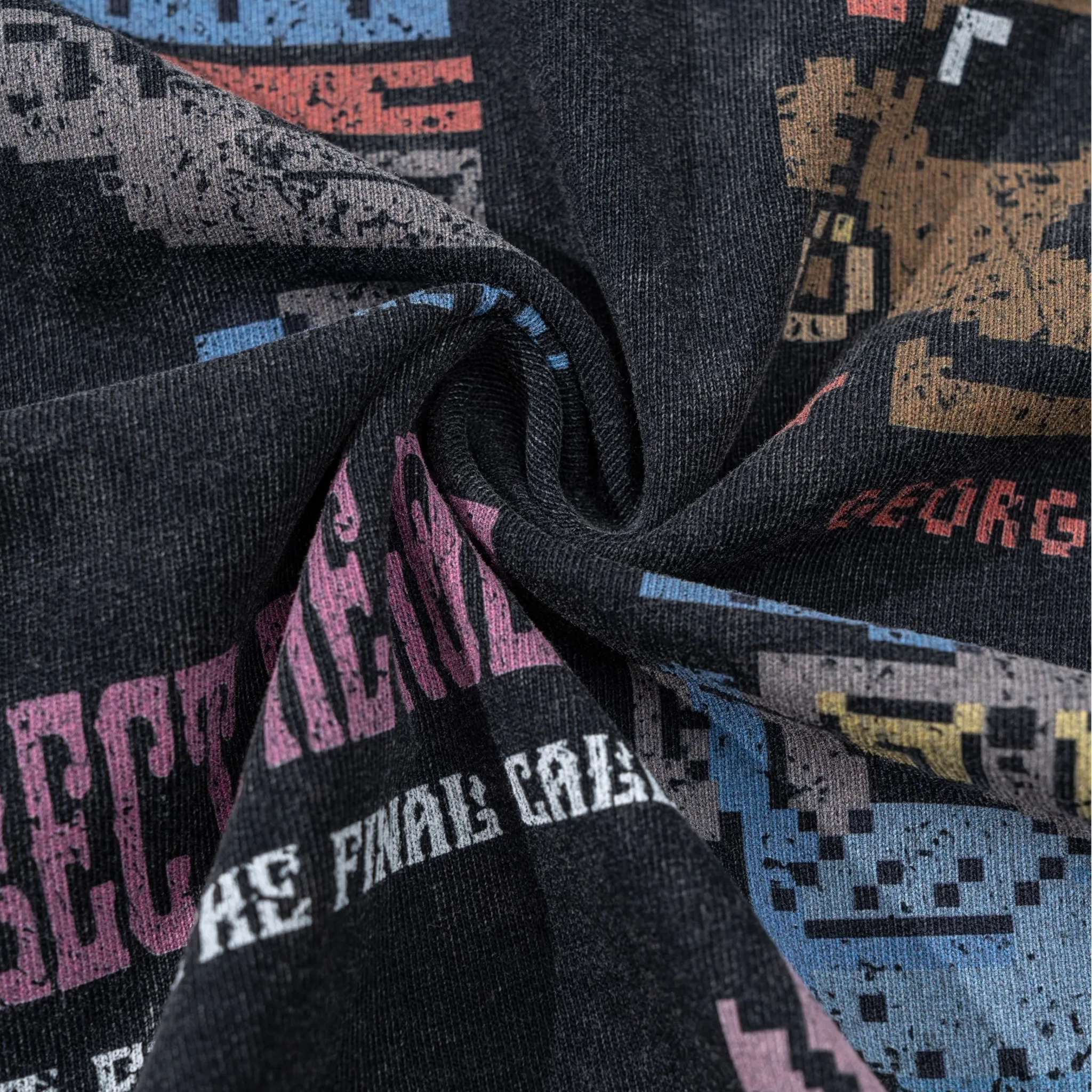 Close-up of fabric with pixelated text and graphics, featuring colors like black, pink, blue, and beige.