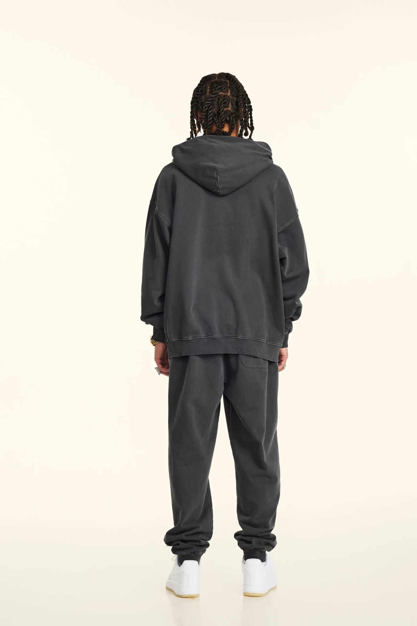 Person wearing a dark gray hoodie and pants on a white background