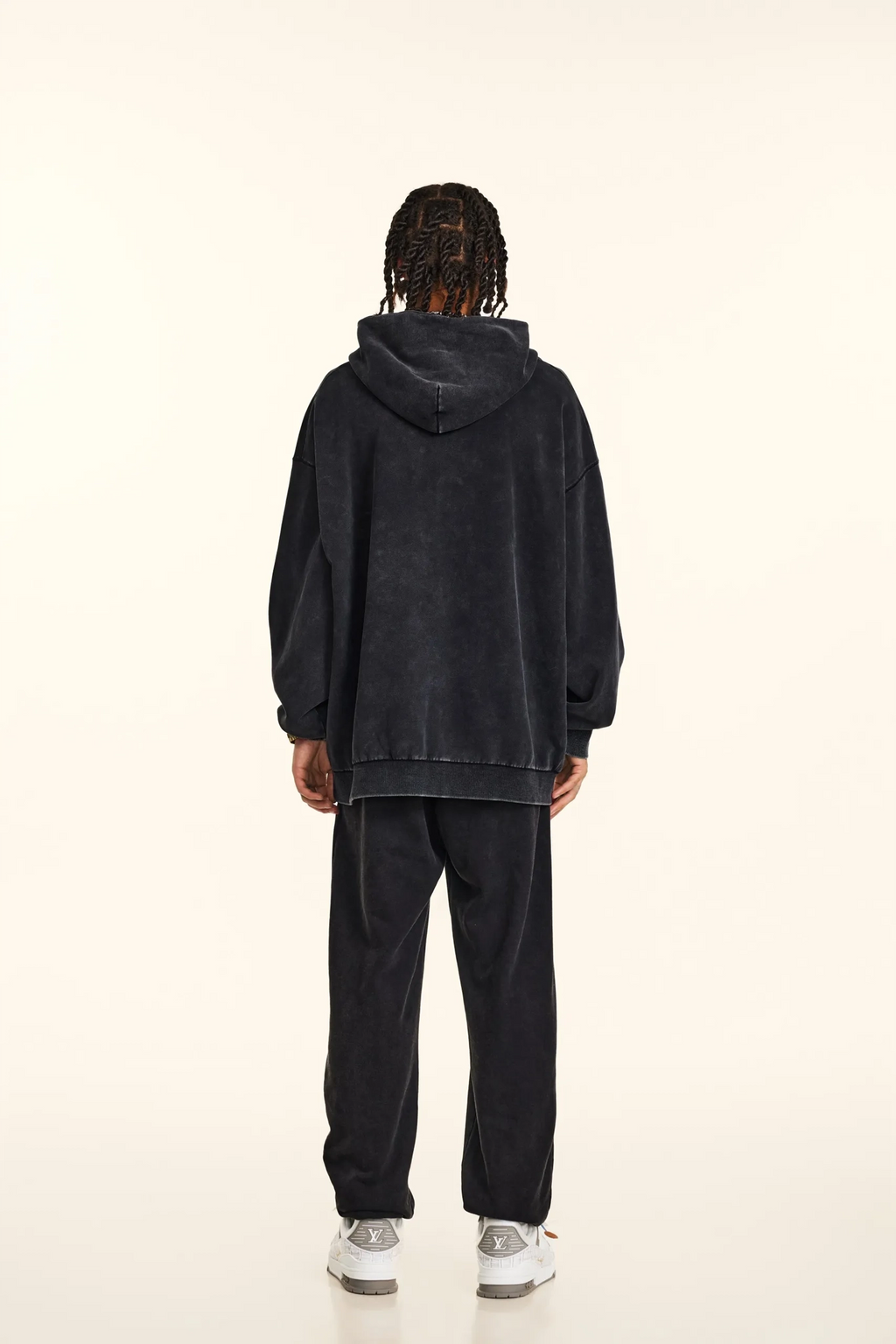 Person wearing a black hoodie and pants on a white background