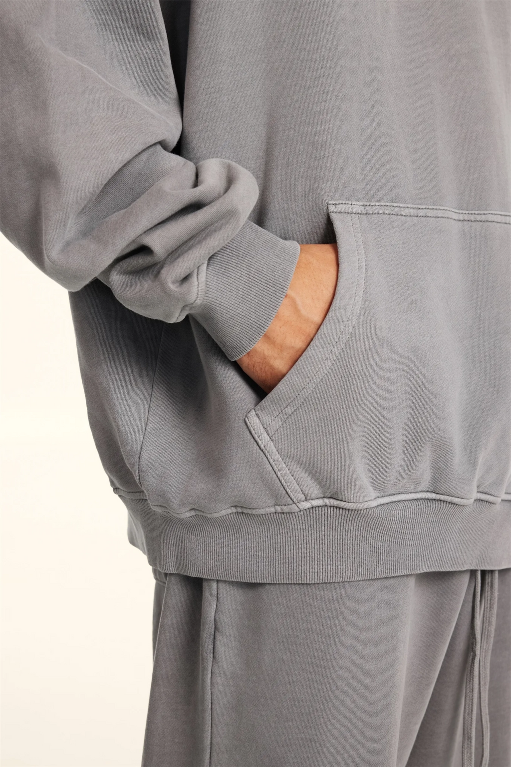 Gray sweatshirt with a pocket showing a wooden object inside on a light gray background