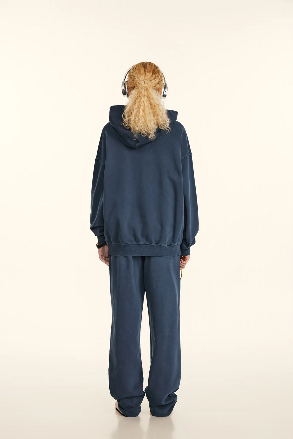 Person wearing a blue tracksuit with headphones on a white background