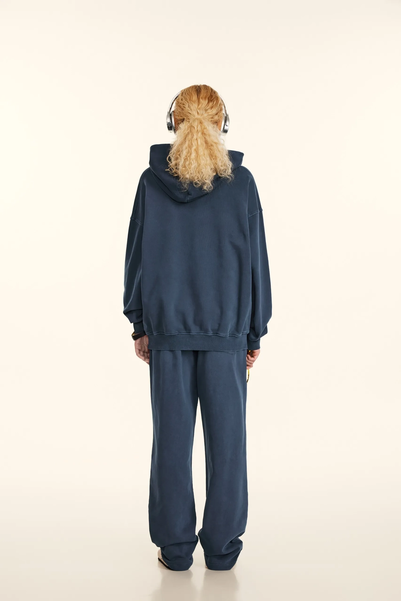 Person wearing a blue tracksuit with headphones on a white background