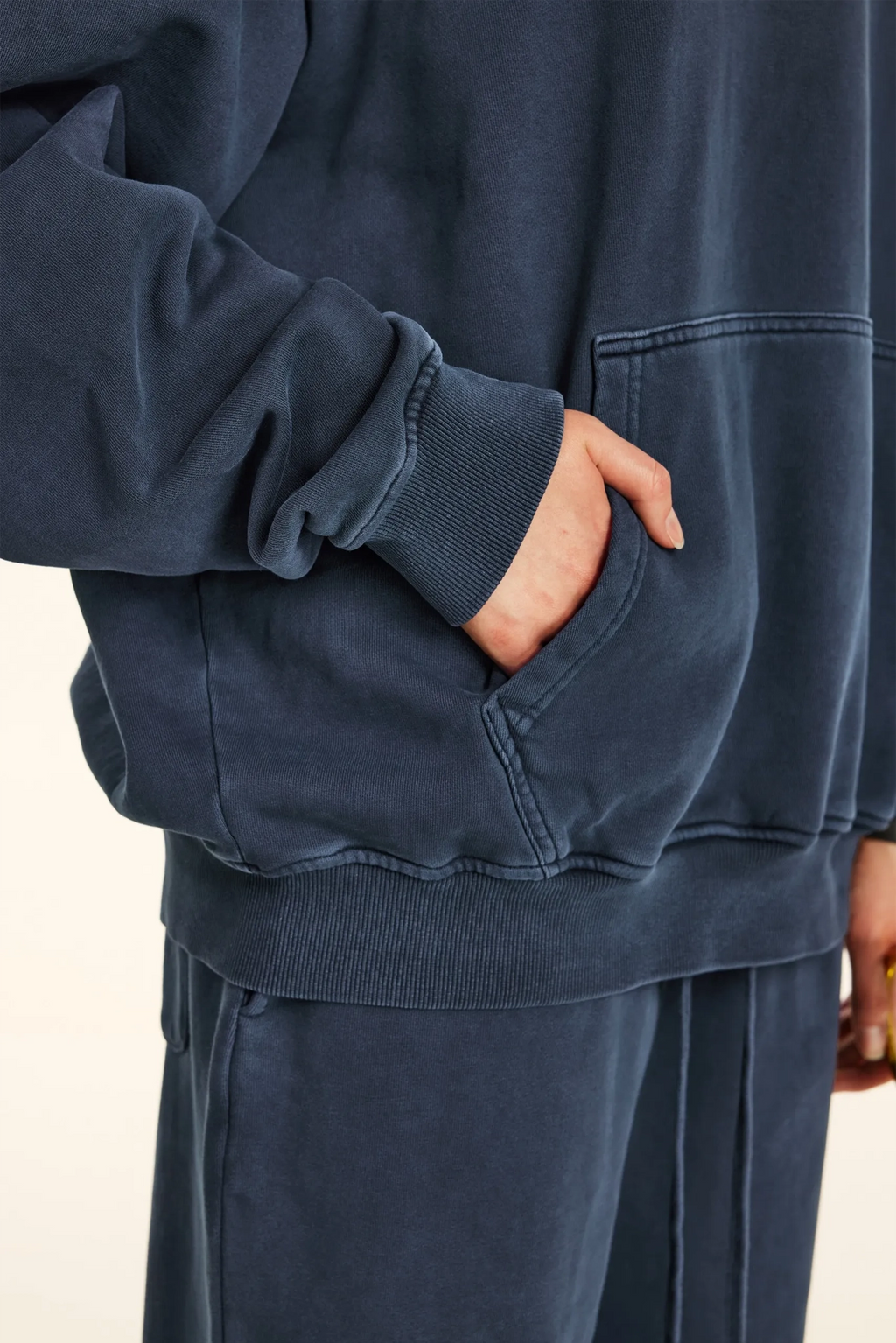 Navy blue sweatshirt and pants worn by a person on a beige background
