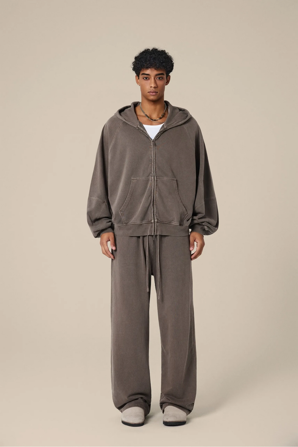 Person wearing a brown tracksuit on a beige background