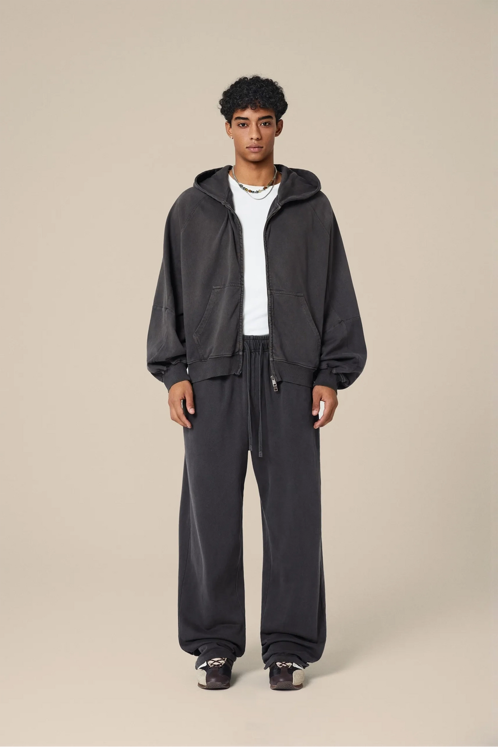 Person wearing a dark gray tracksuit on a beige background