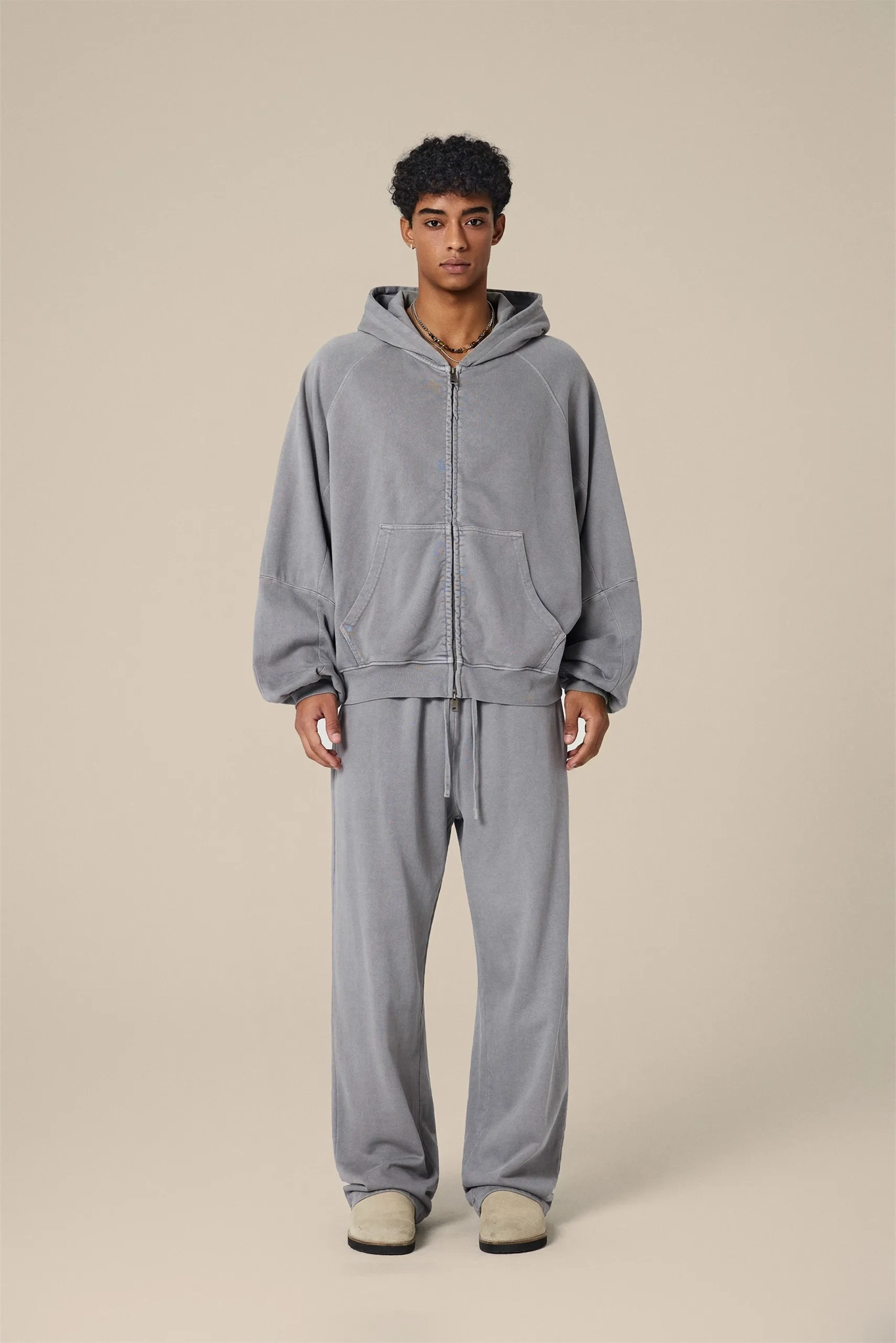 Person wearing a gray tracksuit on a beige background