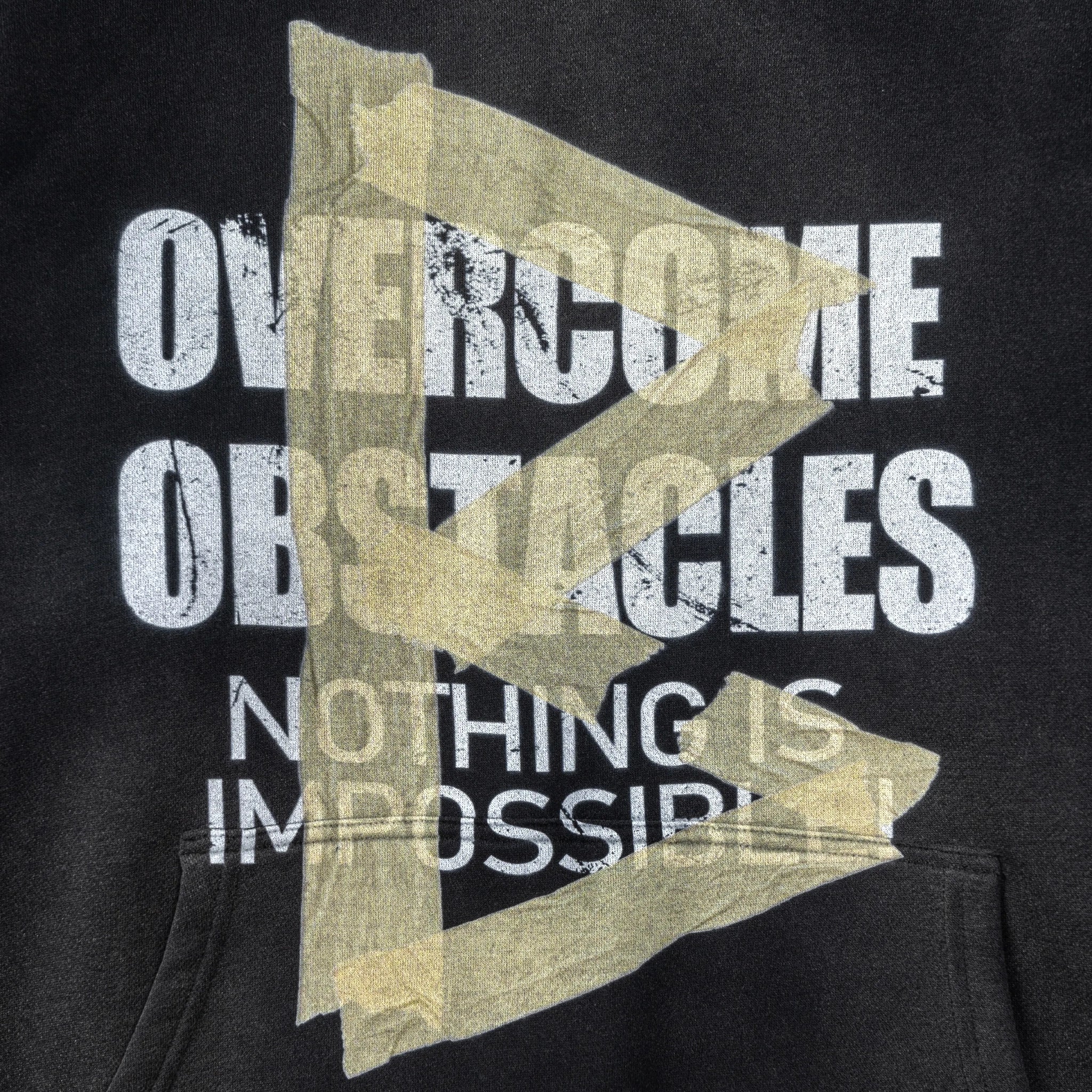 Black hoodie with motivational text 'Overcome Obstacles Nothing is Impossible' in white and gold.