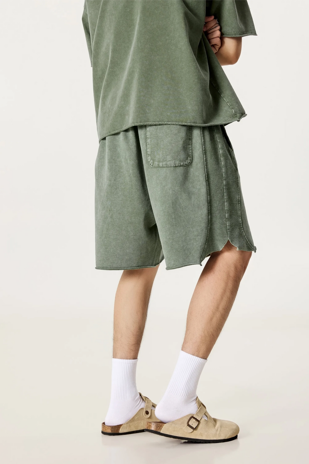 Person wearing a green outfit with shorts and a top on a plain background