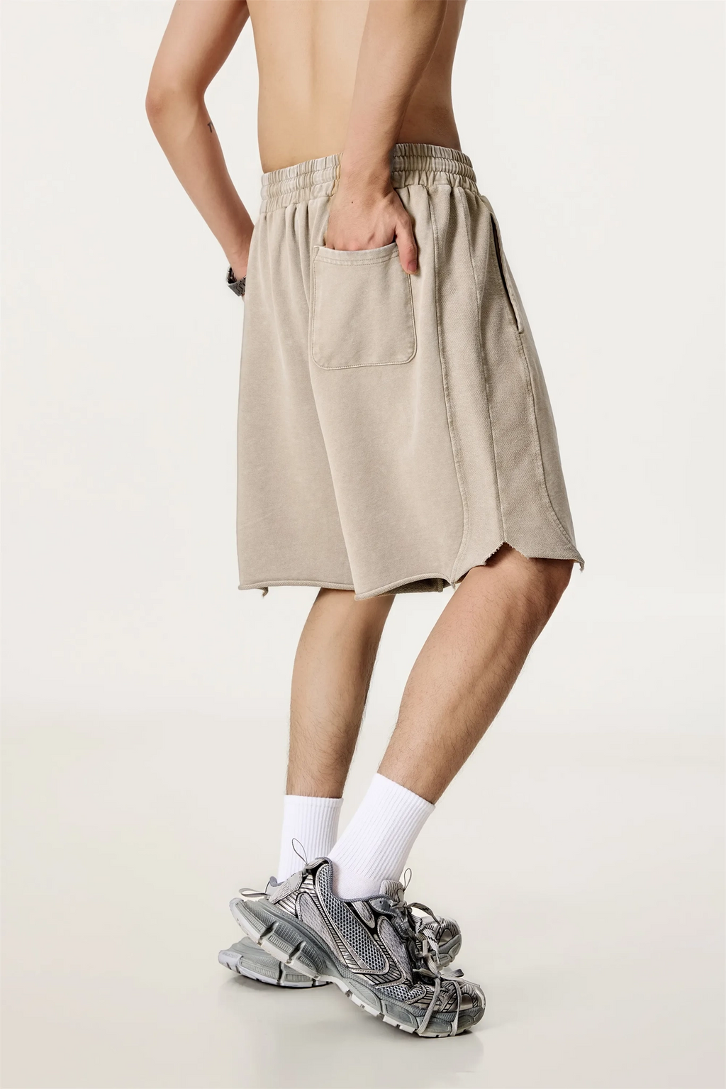 Person wearing beige shorts and white socks on a plain background