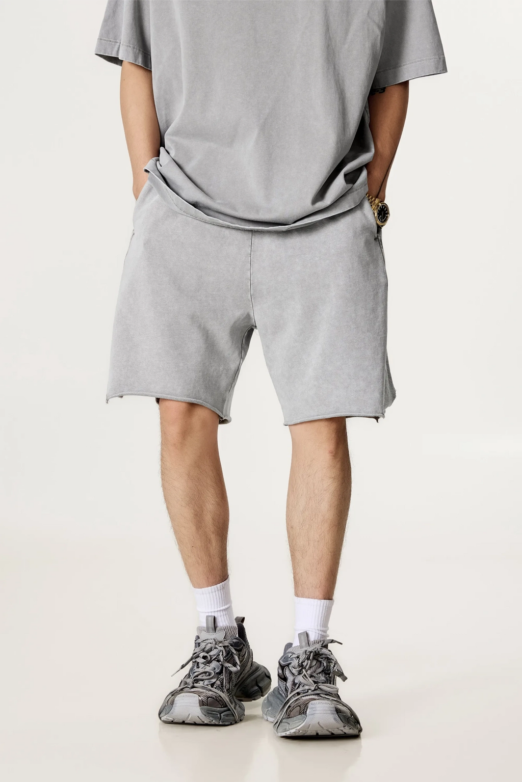 Person wearing a gray t-shirt and shorts with sneakers on a light background