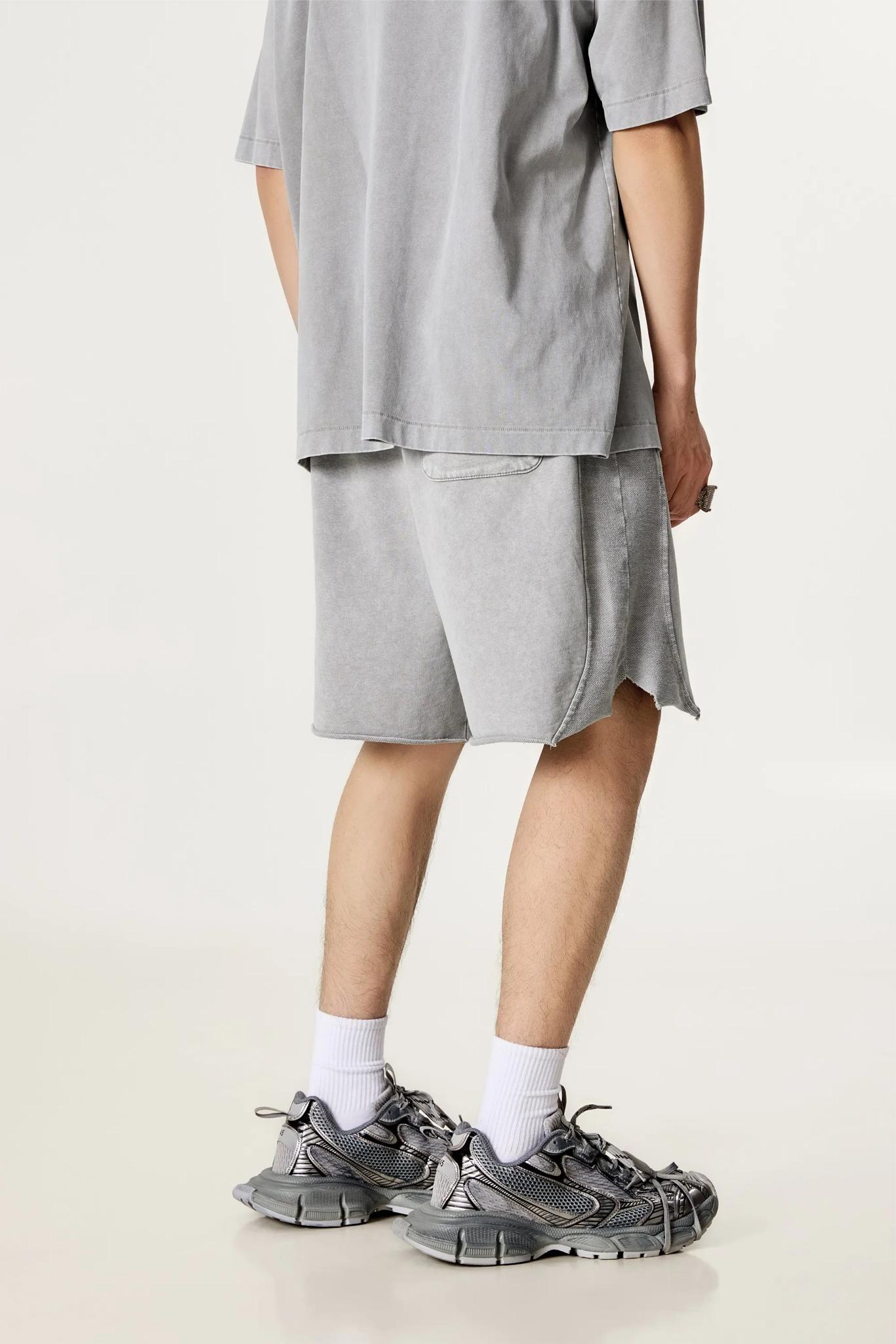 Person wearing a gray outfit with shorts and sneakers on a light background