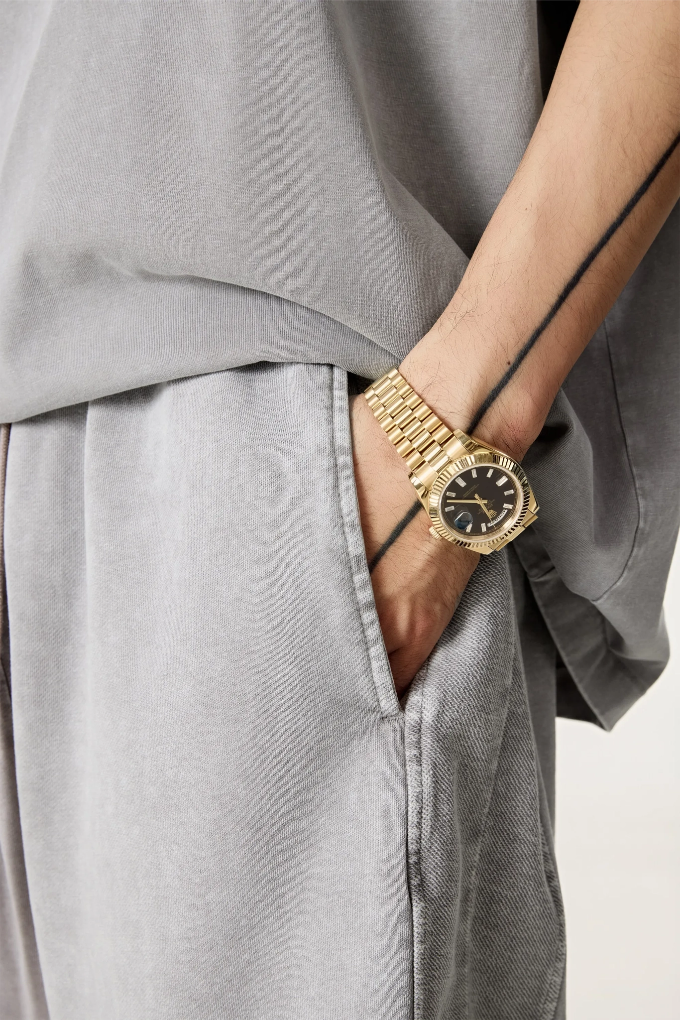 Gold wristwatch on a person's wrist with a neutral background