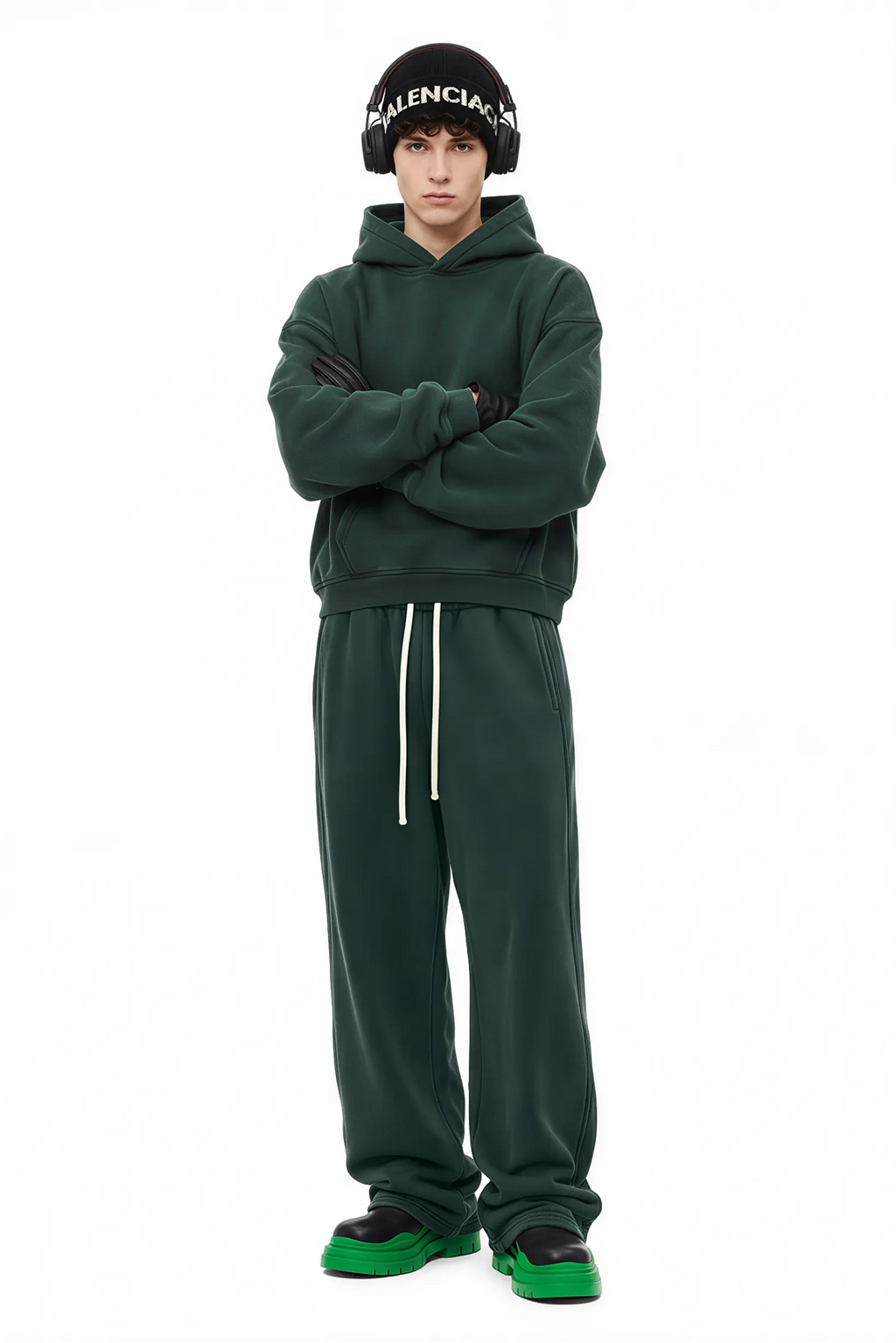 Person wearing a green tracksuit with a Balenciaga beanie on a white background