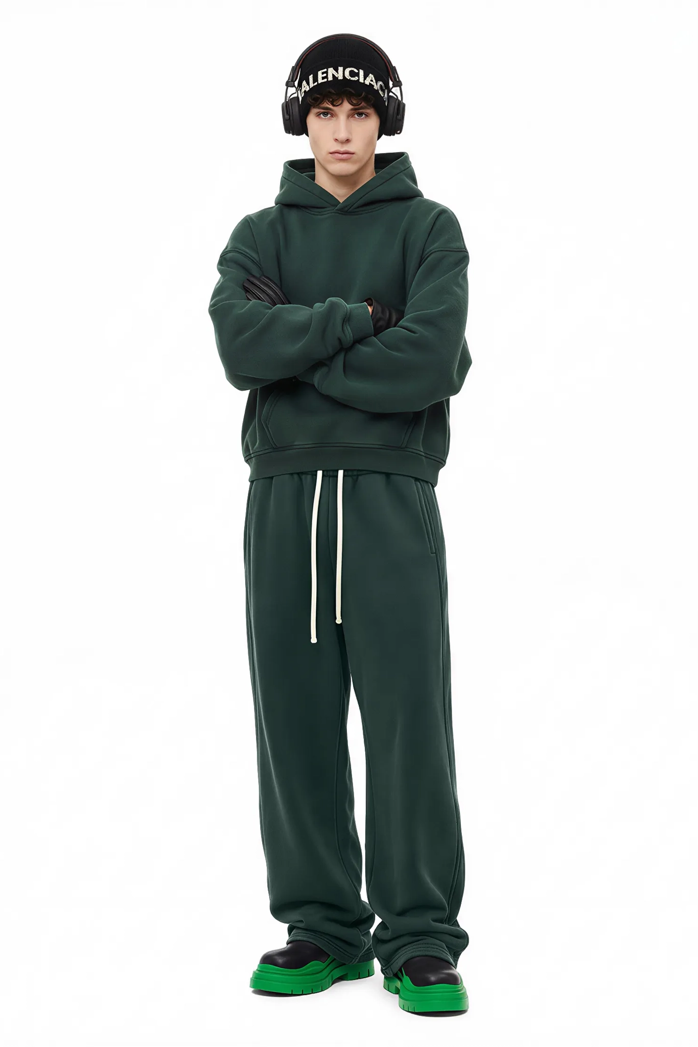 Person wearing a green tracksuit with a Balenciaga beanie on a white background