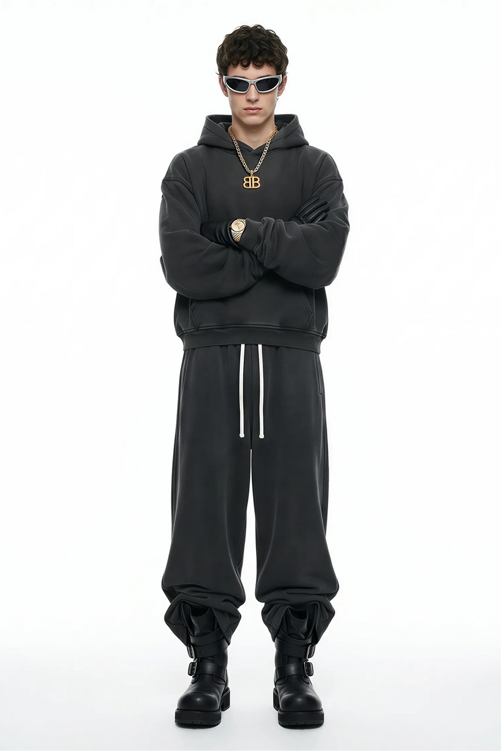 Person wearing a black hoodie and pants with a brand logo, standing against a white background