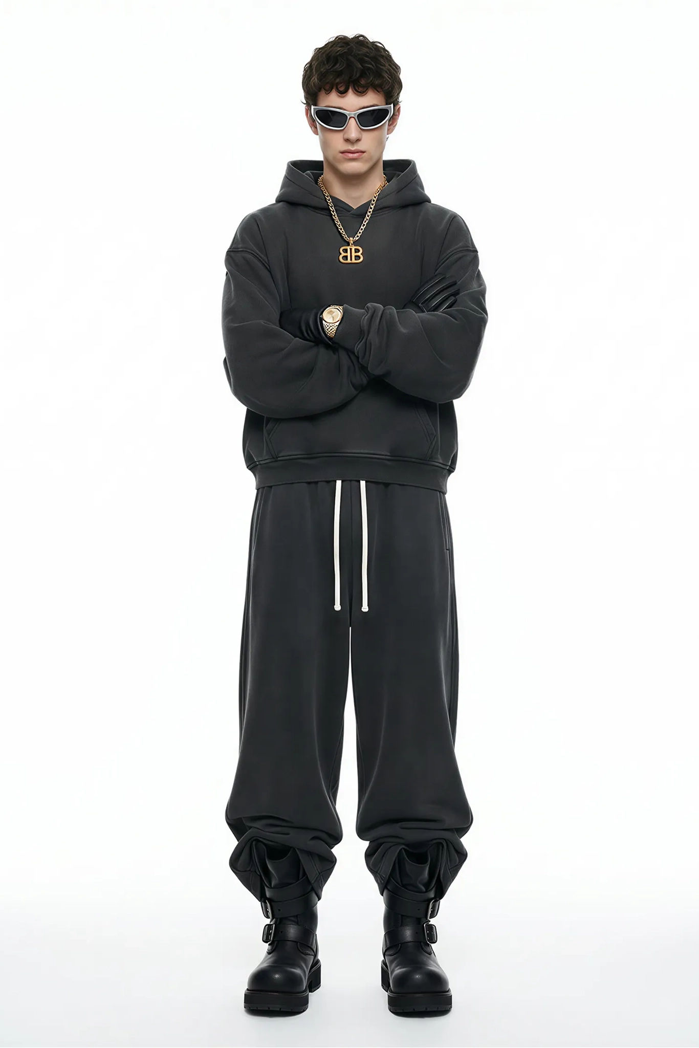 Person wearing a black hoodie and pants with a brand logo, standing against a white background