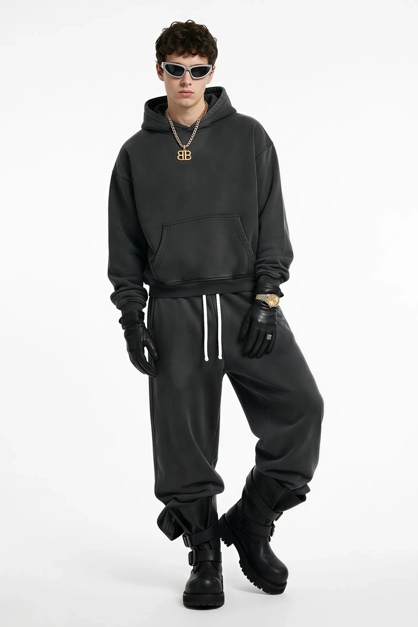 Person wearing a black hoodie, pants, gloves, and boots on a white background