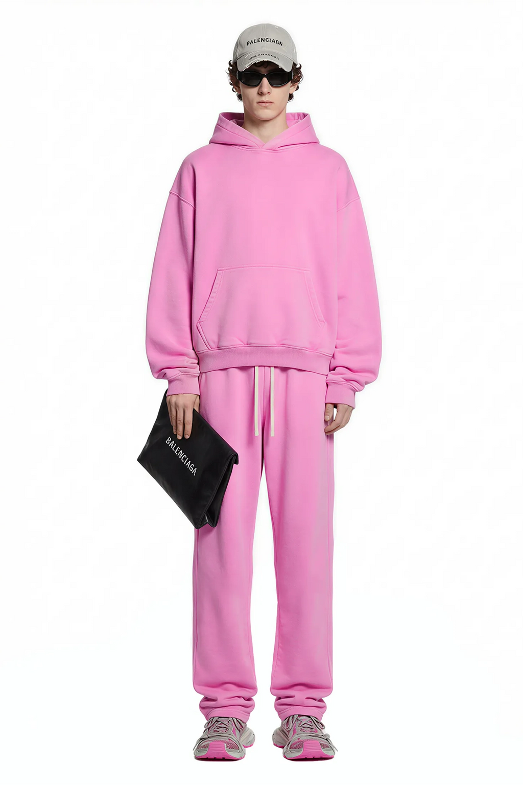 Person wearing a pink tracksuit with a black bag on a white background