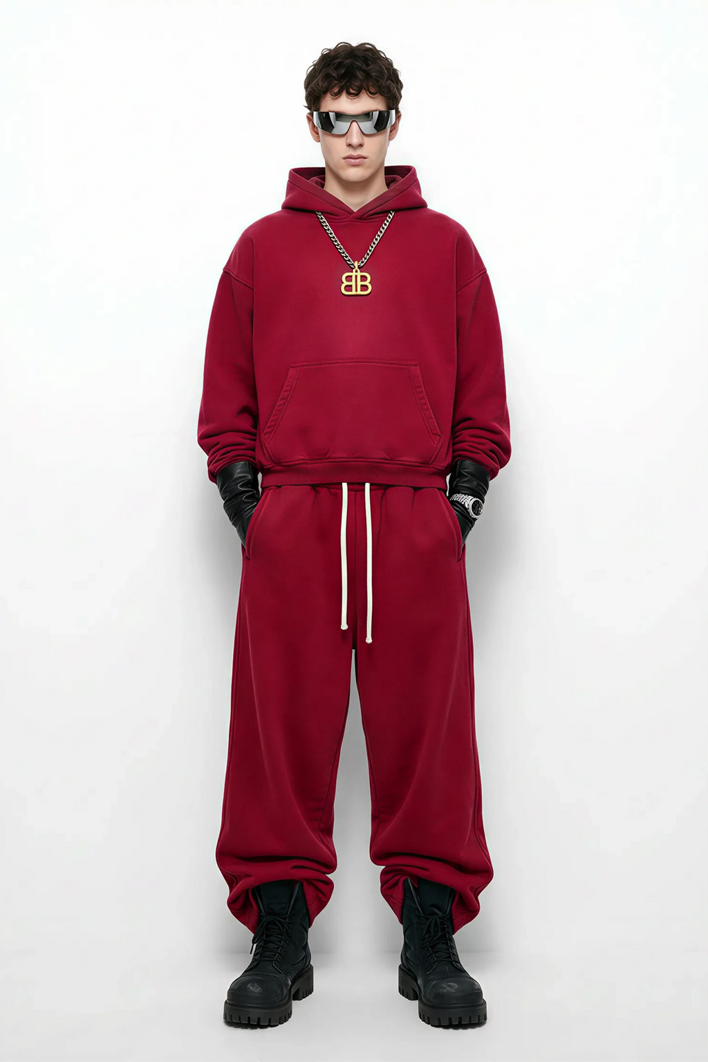 Person wearing a red hoodie and pants with black boots on a white background