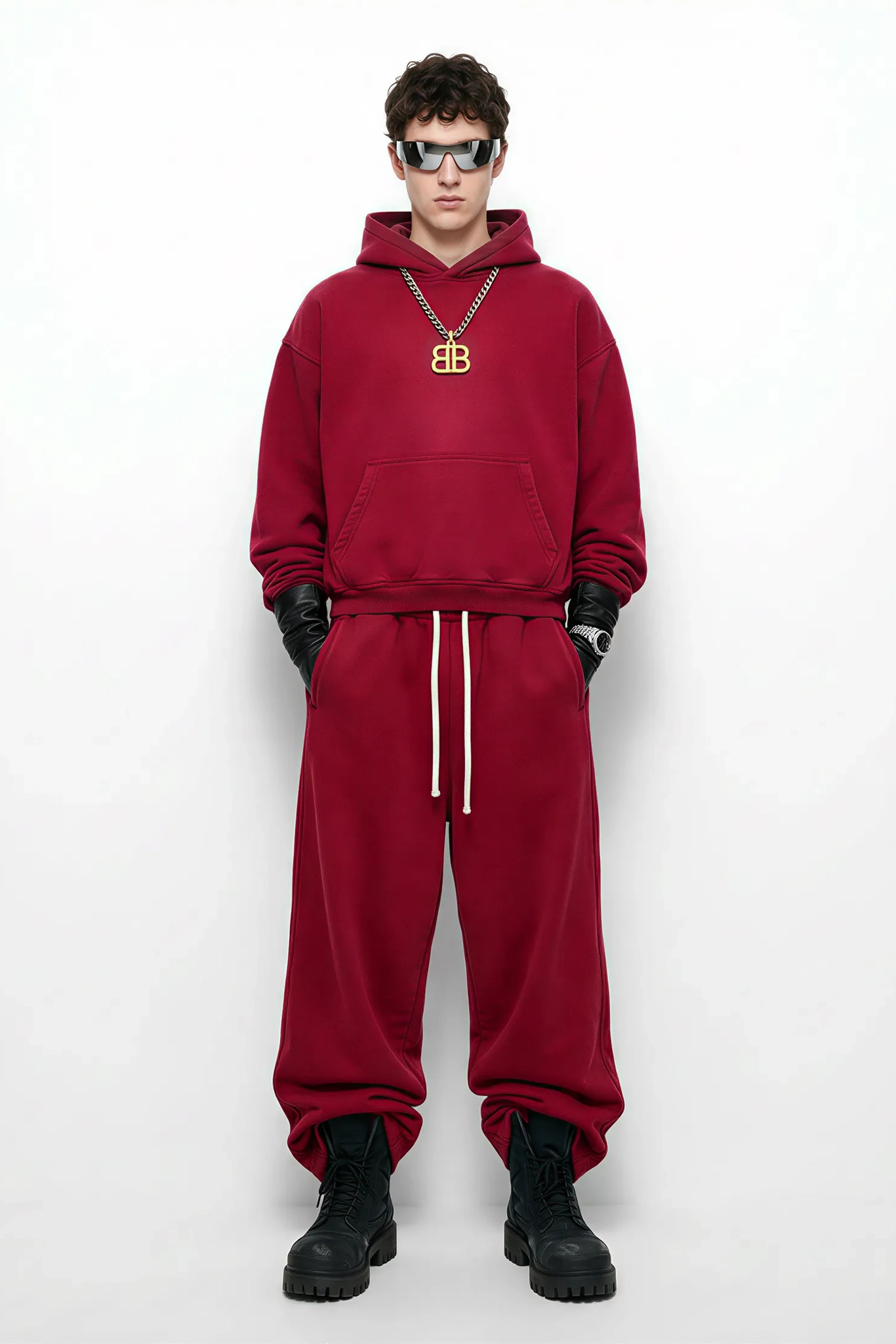 Person wearing a red hoodie and pants with black boots on a white background