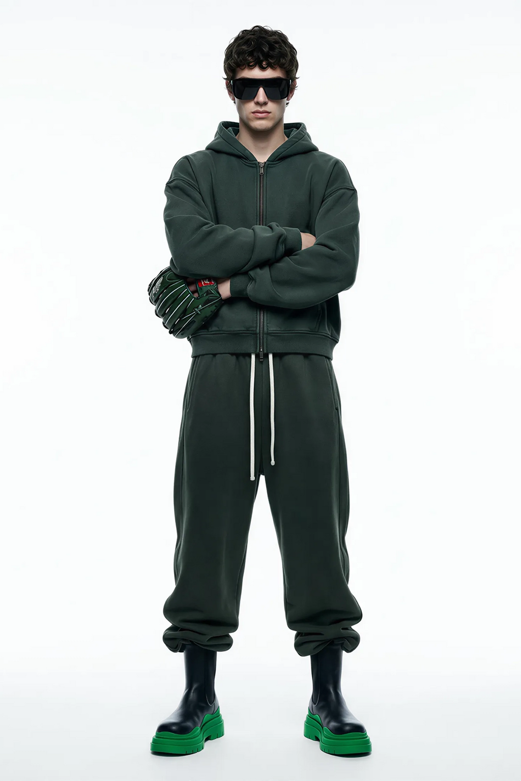 Person wearing a green tracksuit with sunglasses on a white background