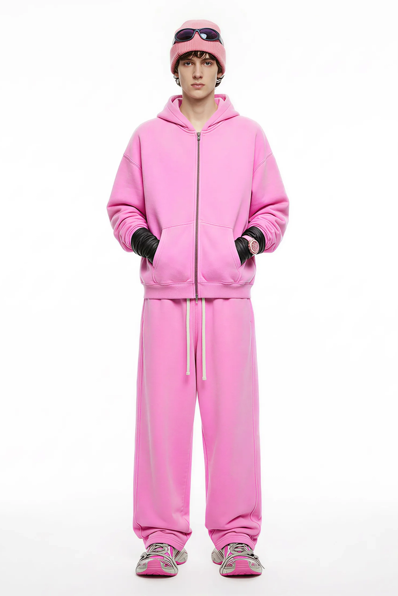Person wearing a pink tracksuit and matching beanie on a white background