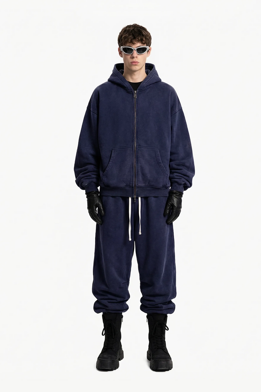 Person wearing a navy blue tracksuit with black gloves and boots on a white background