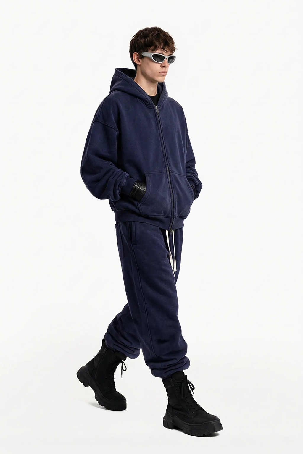 Person wearing a navy blue tracksuit and black boots on a white background