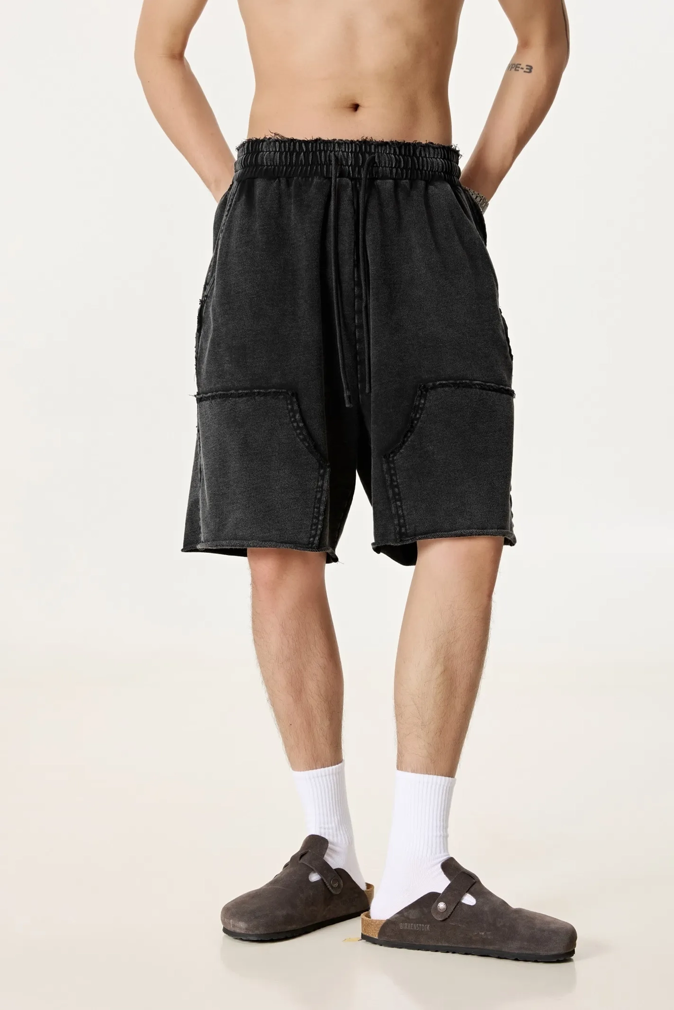Person wearing black shorts on a plain background