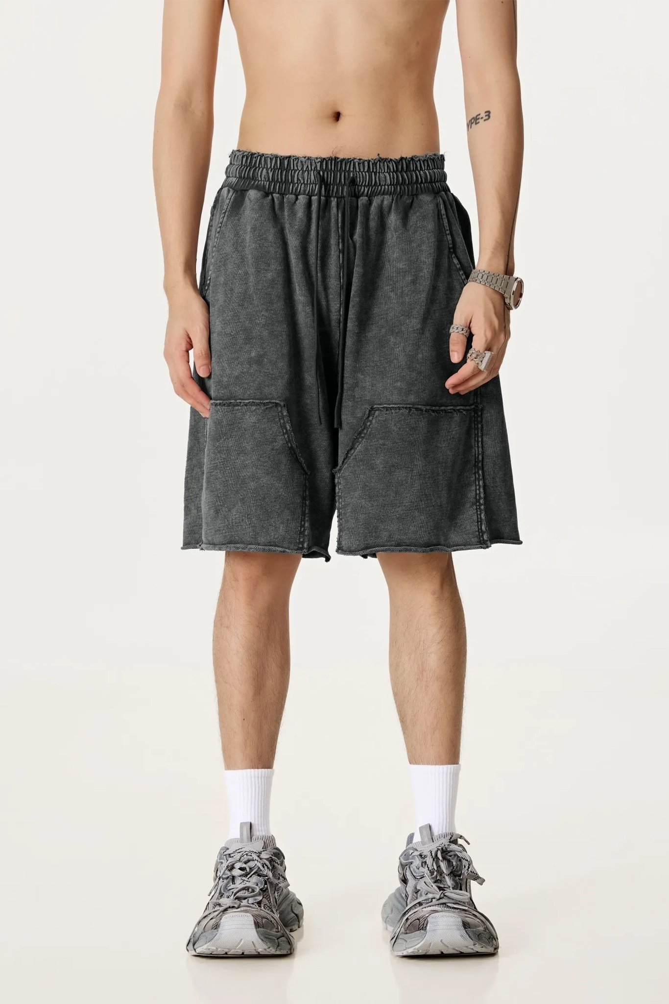 Person wearing dark gray shorts on a plain background