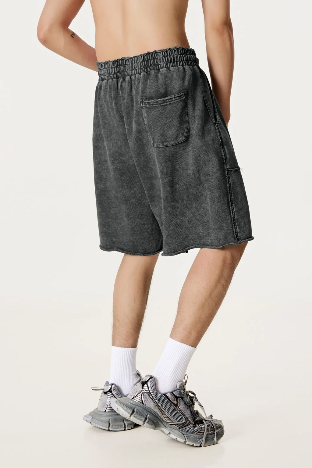 Person wearing dark gray shorts on a white background