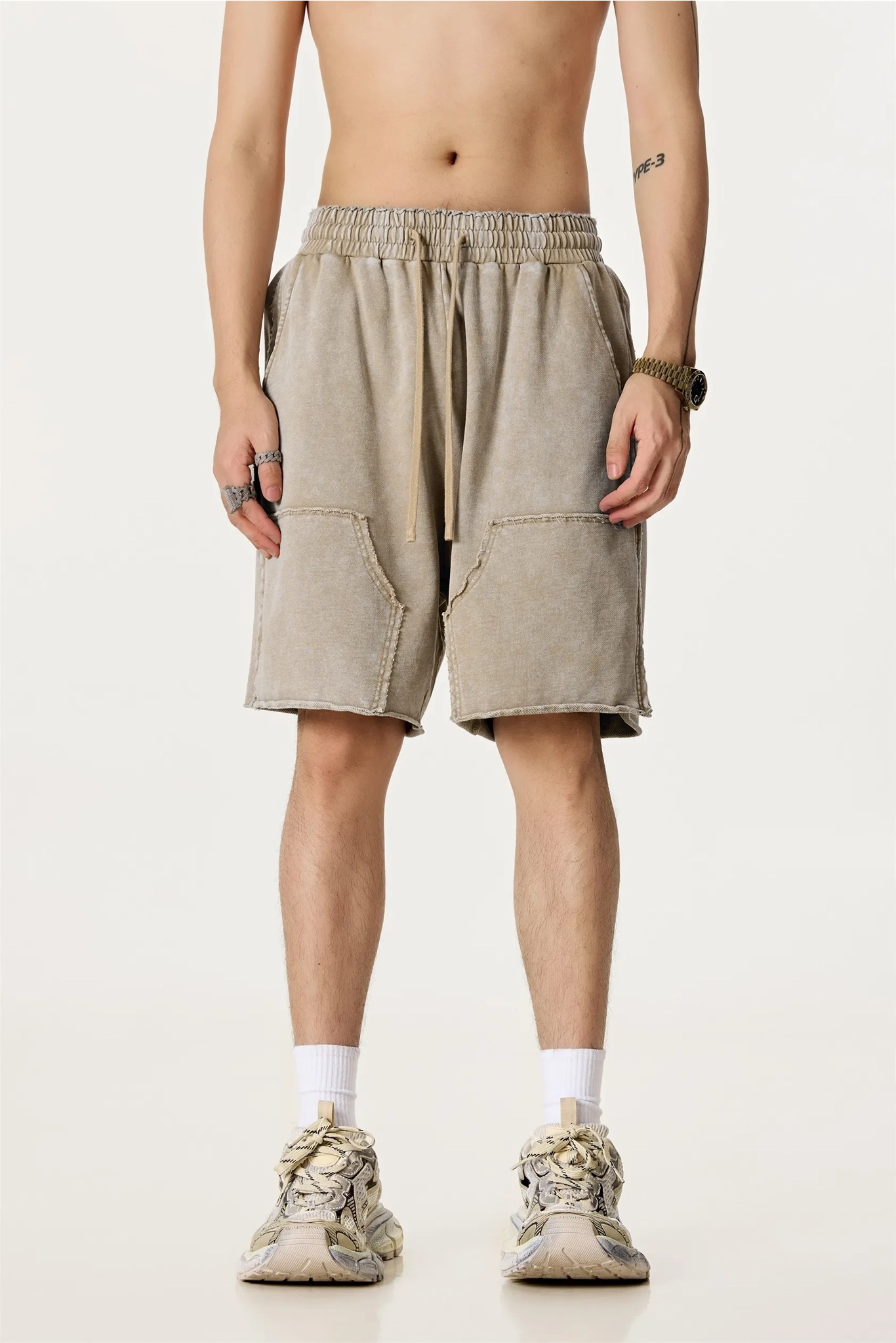 Person wearing beige shorts on a white background