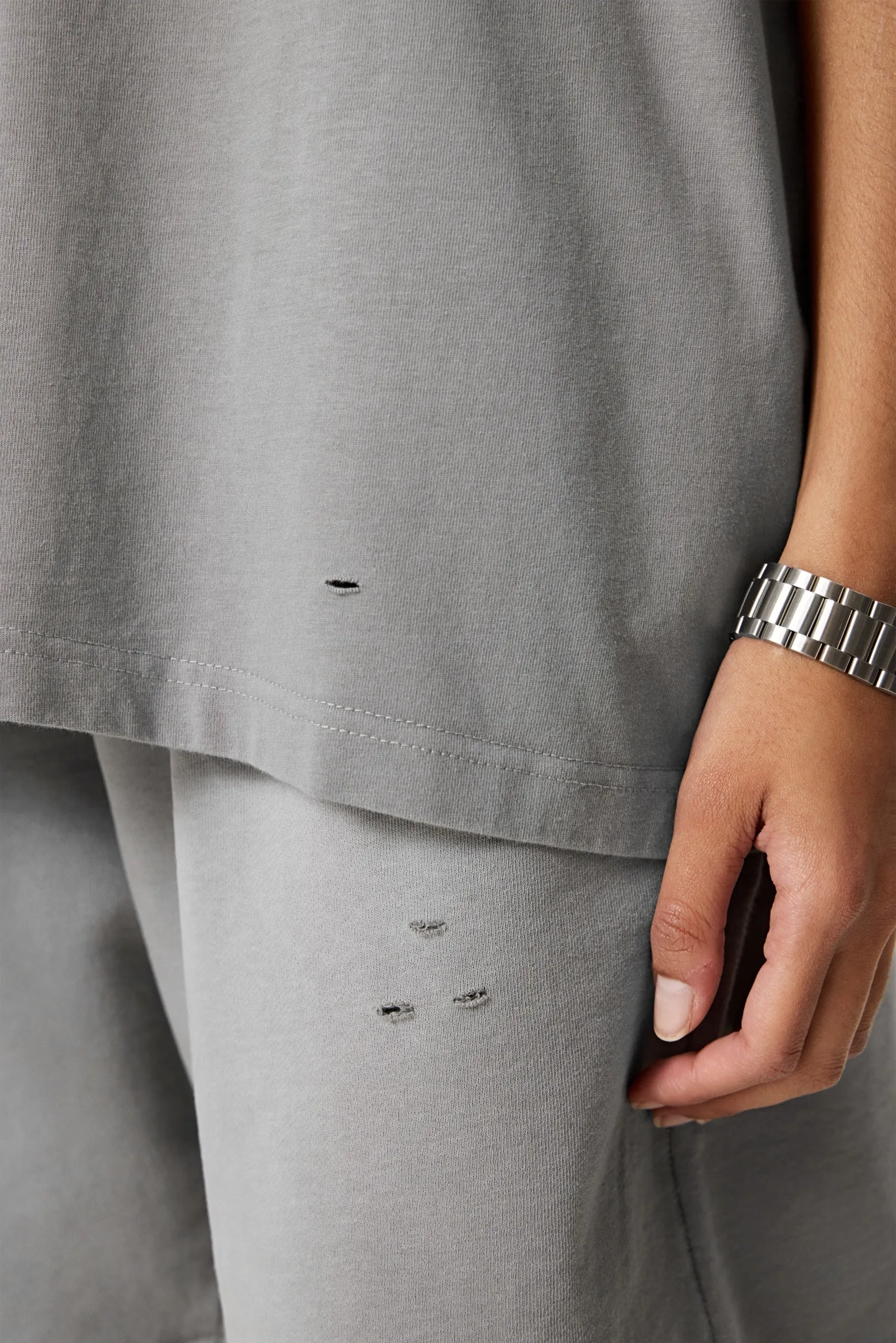 Gray pants with visible wear and tear, worn by a person.